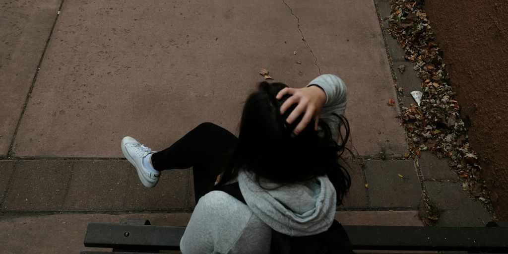 a person sitting on a bench on a sidewalk